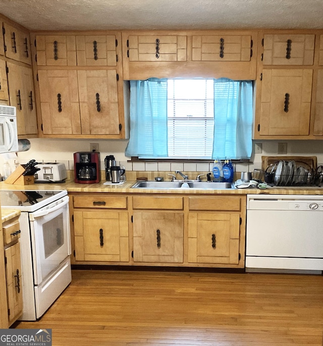 kitchen featuring white appliances, light brown cabinetry, sink, and light wood-type flooring