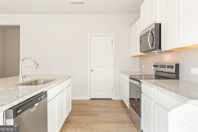 kitchen with light stone counters, appliances with stainless steel finishes, sink, and white cabinets