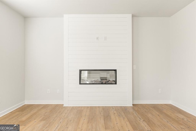 unfurnished living room with a fireplace and light wood-type flooring