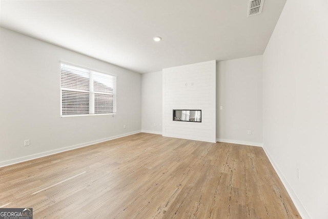 unfurnished living room featuring a fireplace and light hardwood / wood-style floors