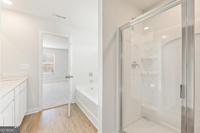 bathroom featuring shower with separate bathtub, wood-type flooring, and vanity