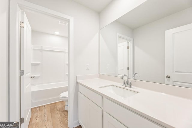 full bathroom with hardwood / wood-style flooring, vanity, shower / tub combination, and toilet