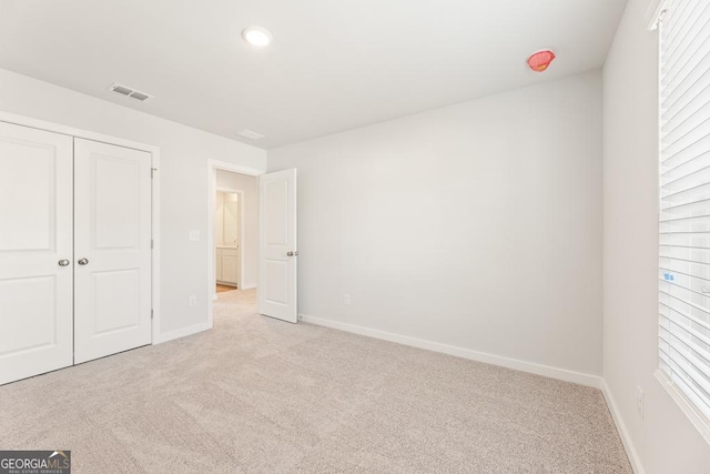 unfurnished bedroom with light carpet and a closet