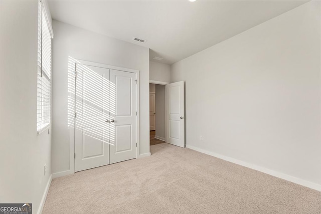 unfurnished bedroom featuring light colored carpet and a closet