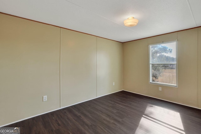 spare room with crown molding and dark wood-type flooring