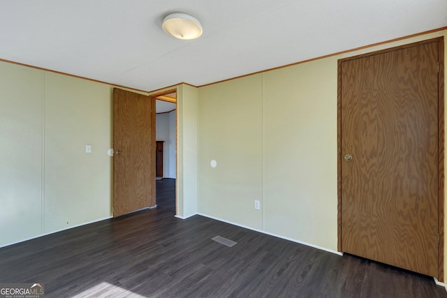 unfurnished bedroom featuring dark wood-type flooring and ornamental molding