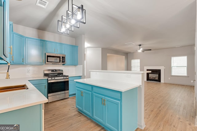3236 Tallon Ln SW, Atlanta, GA 30311 - kitchen featuring appliances with stainless steel finishes, blue cabinets, light wood-type flooring, ceiling fan, and a center island
