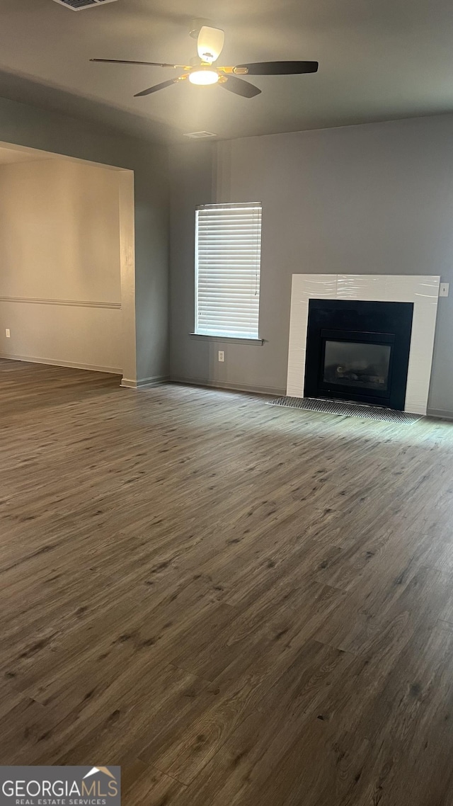 unfurnished living room featuring ceiling fan and dark hardwood / wood-style floors