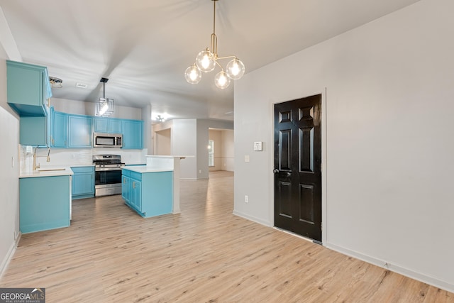 3236 Tallon Ln SW, Atlanta, GA 30311 - kitchen with blue cabinets, appliances with stainless steel finishes, light countertops, a chandelier, and light wood-type flooring