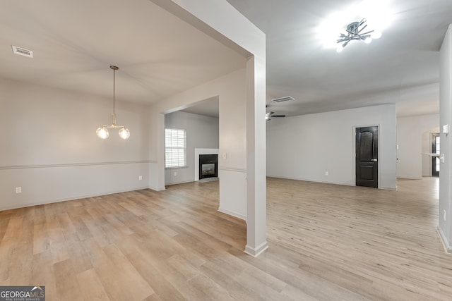 3236 Tallon Ln SW, Atlanta, GA 30311 - unfurnished living room featuring light wood-style flooring, a glass covered fireplace, a ceiling fan, and a chandelier