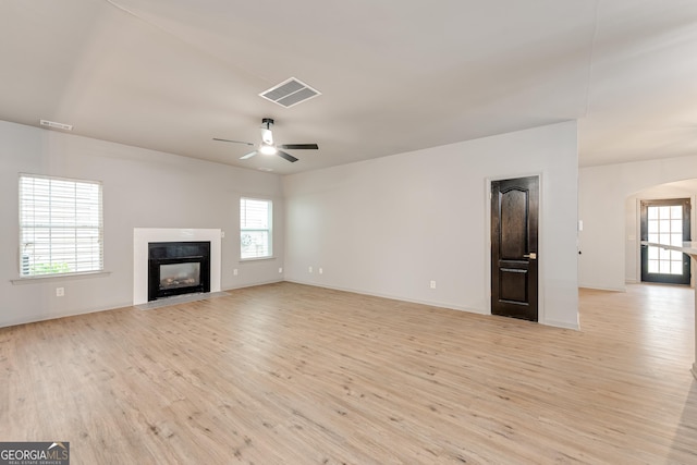 3236 Tallon Ln SW, Atlanta, GA 30311 - unfurnished living room featuring light wood-type flooring, a fireplace with flush hearth, ceiling fan, and arched walkways