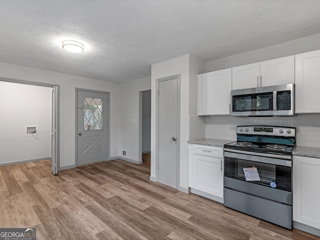 kitchen featuring tasteful backsplash, appliances with stainless steel finishes, white cabinets, and light wood-type flooring