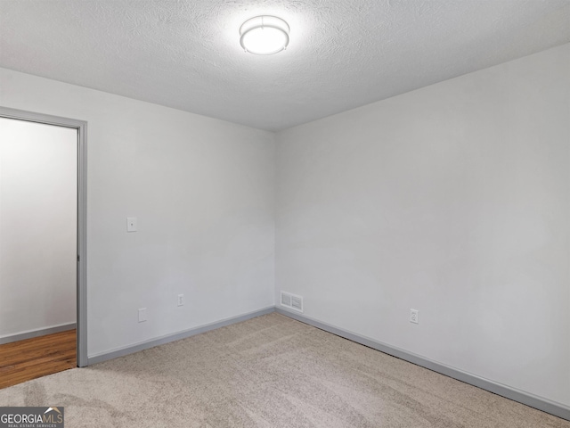 carpeted empty room featuring a textured ceiling