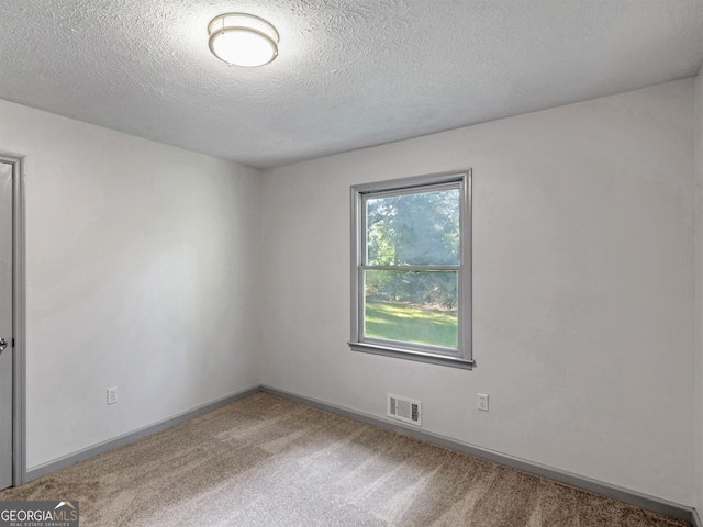 carpeted spare room featuring a textured ceiling