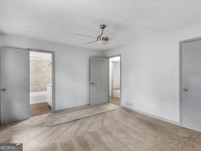 unfurnished bedroom with connected bathroom, ceiling fan, a textured ceiling, and carpet flooring