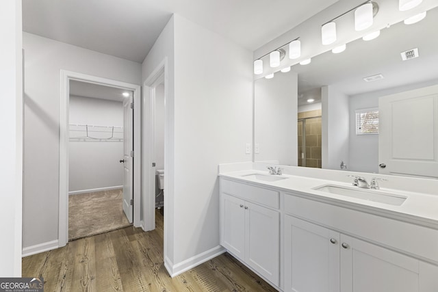 bathroom featuring vanity, hardwood / wood-style floors, walk in shower, and toilet