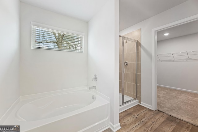 bathroom featuring wood-type flooring and shower with separate bathtub