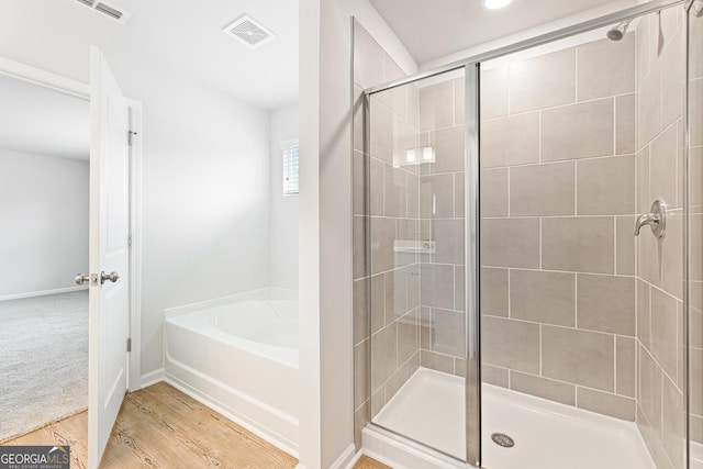 bathroom with hardwood / wood-style flooring and separate shower and tub