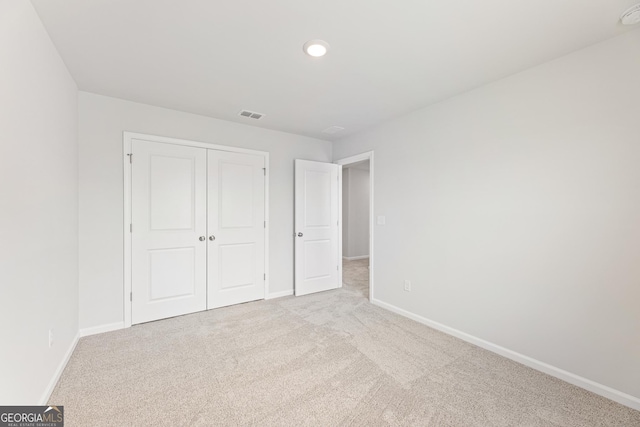 unfurnished bedroom featuring light carpet and a closet