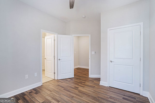 unfurnished bedroom with ceiling fan, dark wood-type flooring, and ensuite bath