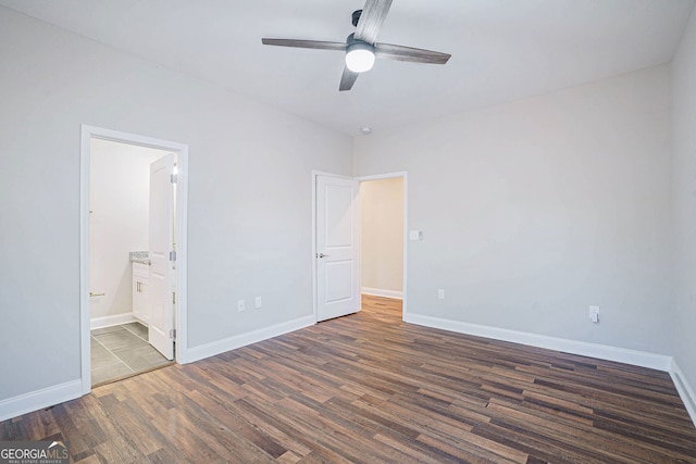 unfurnished bedroom featuring ceiling fan, dark wood-type flooring, and ensuite bath