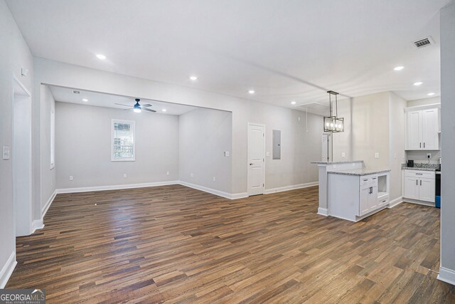 kitchen with dark wood-type flooring, ceiling fan, electric panel, white cabinets, and decorative light fixtures