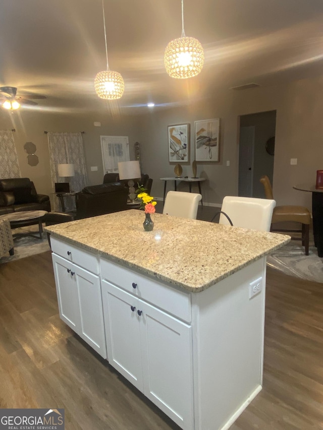 kitchen featuring decorative light fixtures, dark wood-type flooring, white cabinets, and a kitchen island