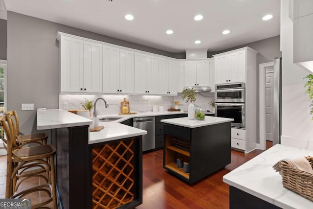 kitchen featuring appliances with stainless steel finishes, white cabinetry, sink, a breakfast bar area, and kitchen peninsula