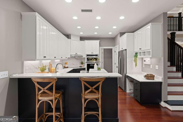 kitchen featuring appliances with stainless steel finishes, a kitchen breakfast bar, kitchen peninsula, and white cabinets