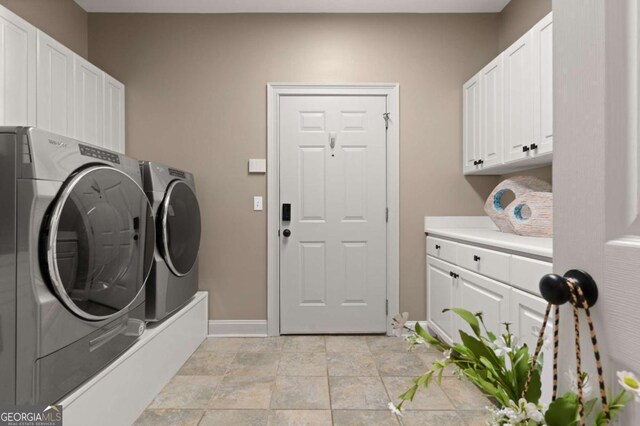 clothes washing area with cabinets and washing machine and clothes dryer