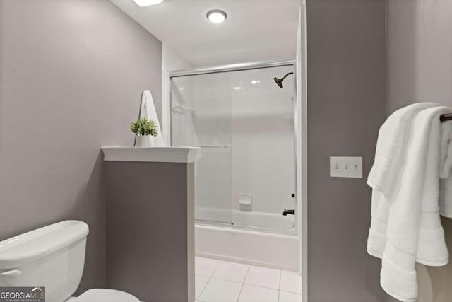 bathroom featuring tile patterned flooring, enclosed tub / shower combo, and toilet