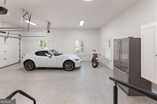 garage with a garage door opener and stainless steel refrigerator