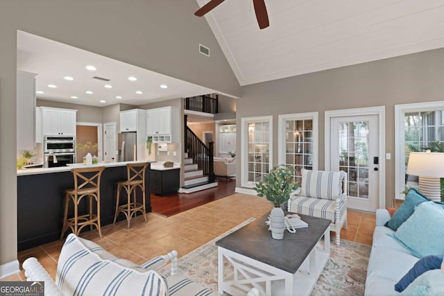 tiled living room with ceiling fan and high vaulted ceiling