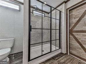 bathroom with walk in shower, wood-type flooring, and toilet