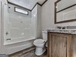 full bathroom with washtub / shower combination, toilet, crown molding, vanity, and hardwood / wood-style floors