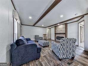 living room with hardwood / wood-style flooring, a large fireplace, and beam ceiling