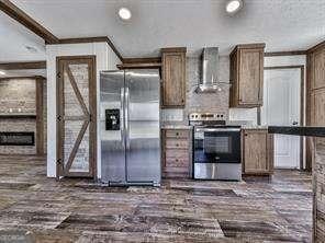 kitchen featuring dark hardwood / wood-style flooring, ornamental molding, wall chimney exhaust hood, and appliances with stainless steel finishes