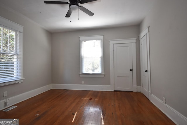 unfurnished room featuring dark hardwood / wood-style flooring, a wealth of natural light, and ceiling fan