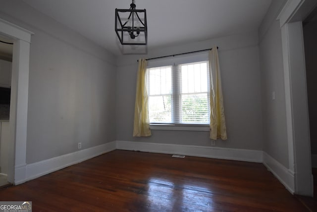 unfurnished room with dark hardwood / wood-style floors and a chandelier