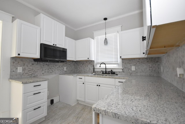 kitchen with ornamental molding, decorative light fixtures, sink, and white cabinets