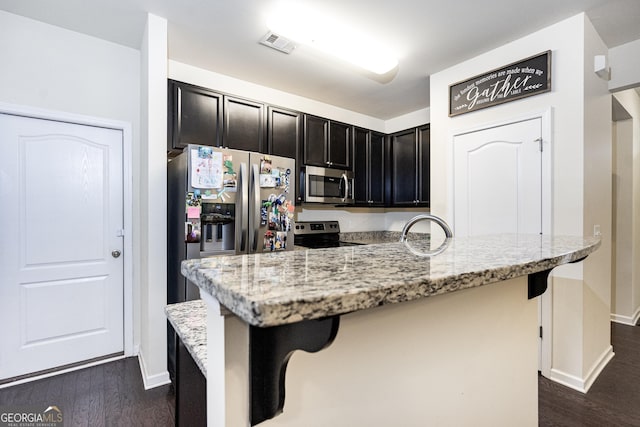 kitchen with visible vents, a kitchen bar, appliances with stainless steel finishes, and light stone counters