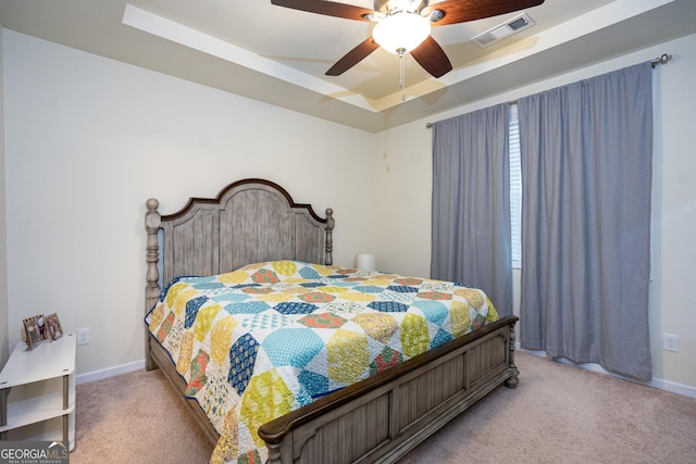 carpeted bedroom featuring a raised ceiling and ceiling fan