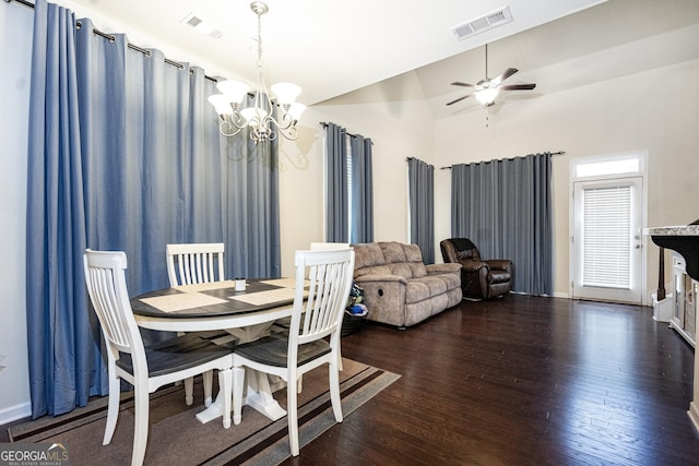 dining area featuring dark hardwood / wood-style flooring, ceiling fan with notable chandelier, and vaulted ceiling