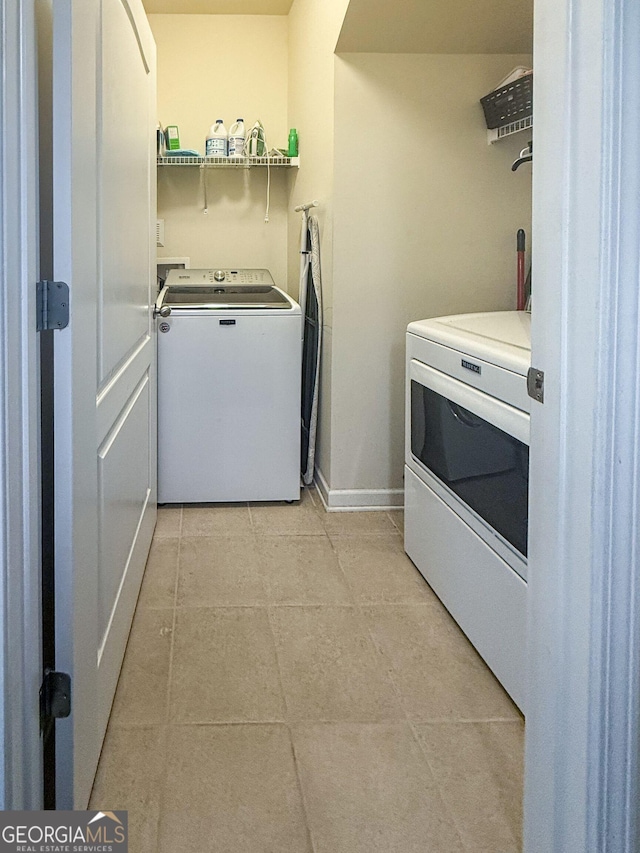 laundry room with washer and dryer, laundry area, light tile patterned flooring, and baseboards