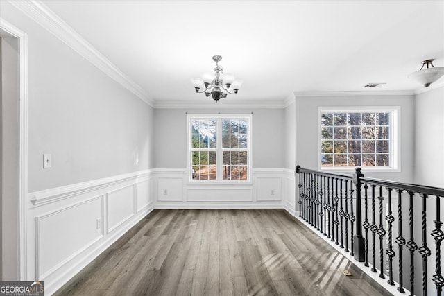 unfurnished dining area featuring a notable chandelier, crown molding, and light wood-type flooring