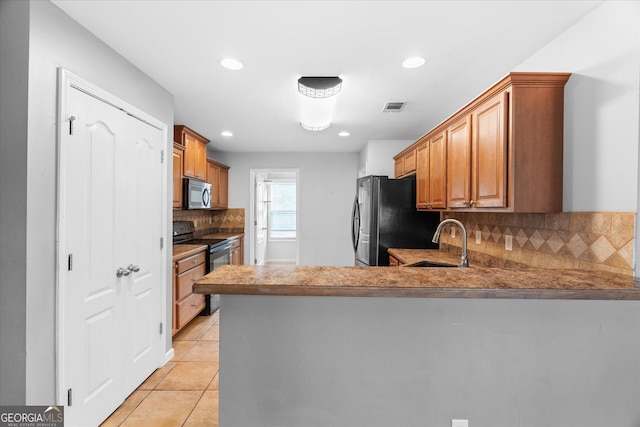 kitchen featuring light tile patterned floors, sink, black appliances, and kitchen peninsula