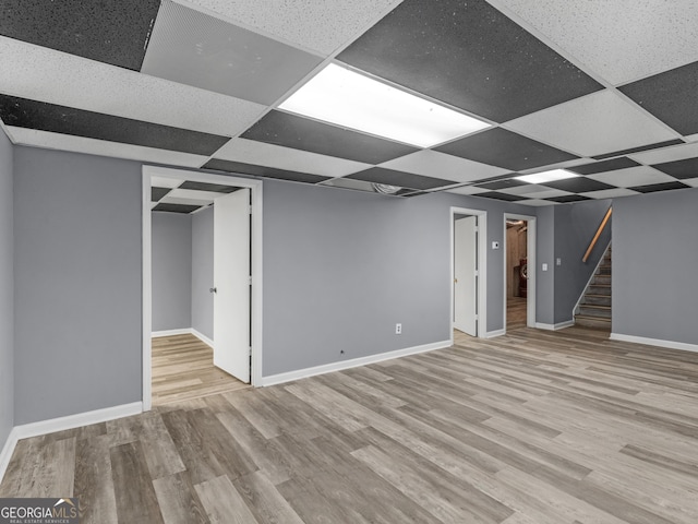 basement featuring a drop ceiling and light hardwood / wood-style floors