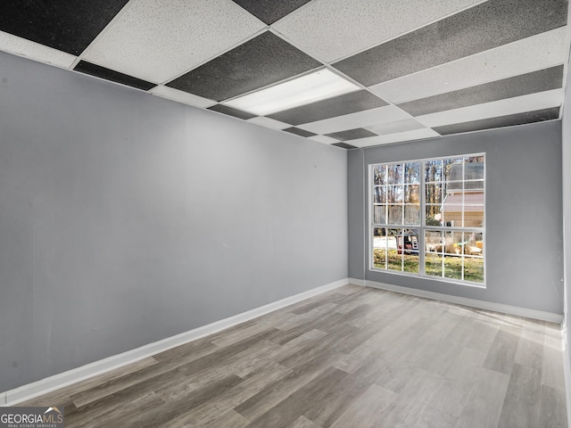 empty room with a drop ceiling and hardwood / wood-style flooring