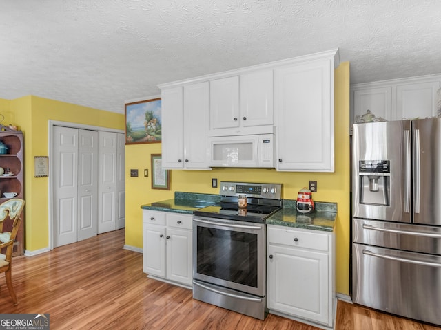 kitchen featuring a textured ceiling, light hardwood / wood-style flooring, stainless steel appliances, and white cabinets