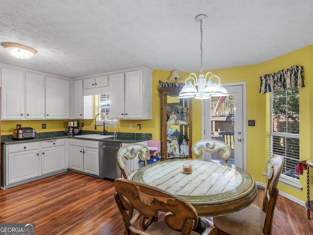 dining space with sink, dark wood-type flooring, a notable chandelier, and a textured ceiling